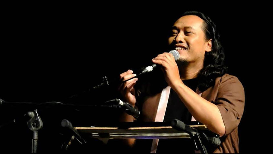 Bagus Mazasupa Headshot musician at a keyboard smiling and singing into microphone page