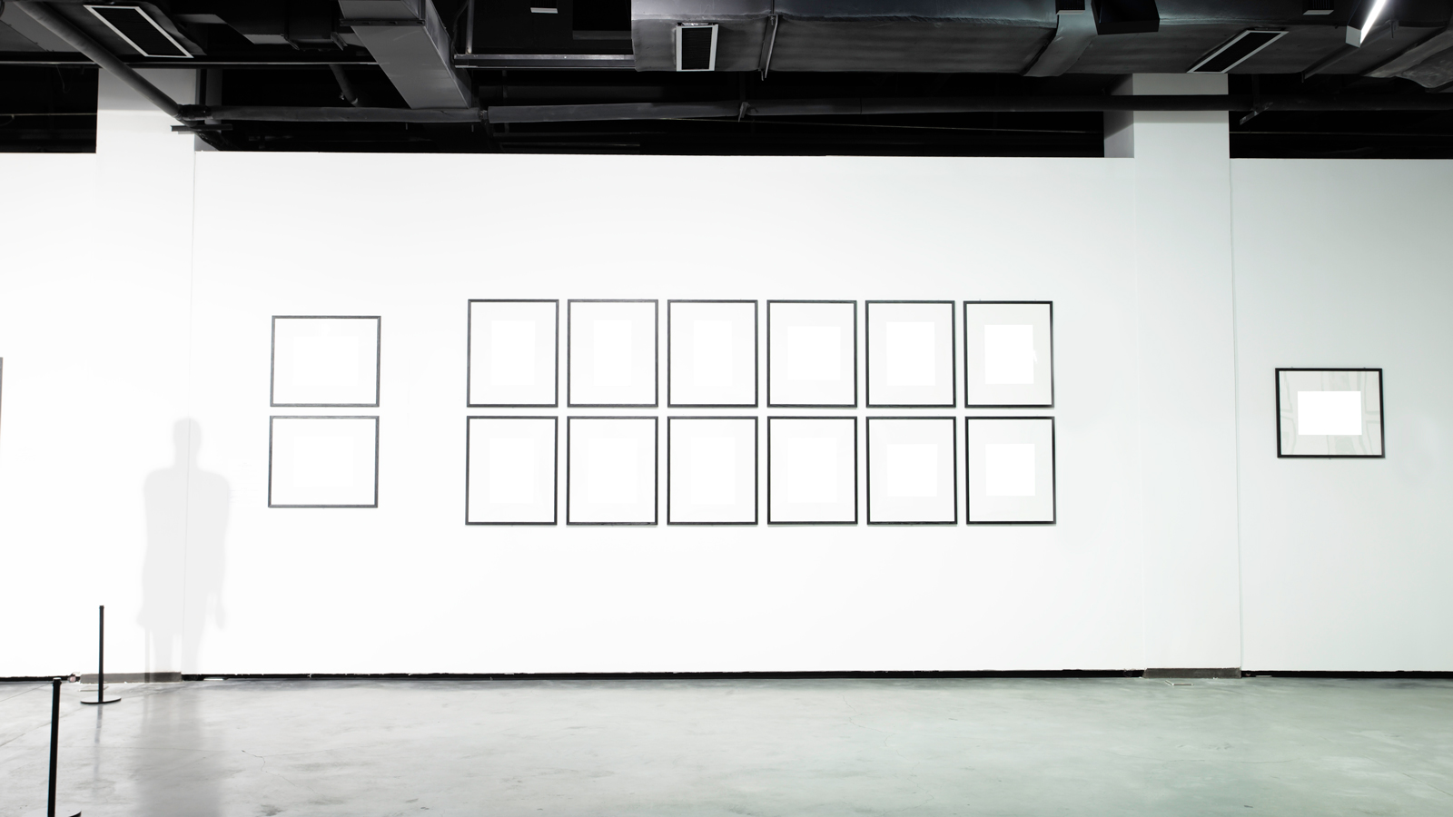 Image is a white art gallery with blank artworks and the shadow of a human figure