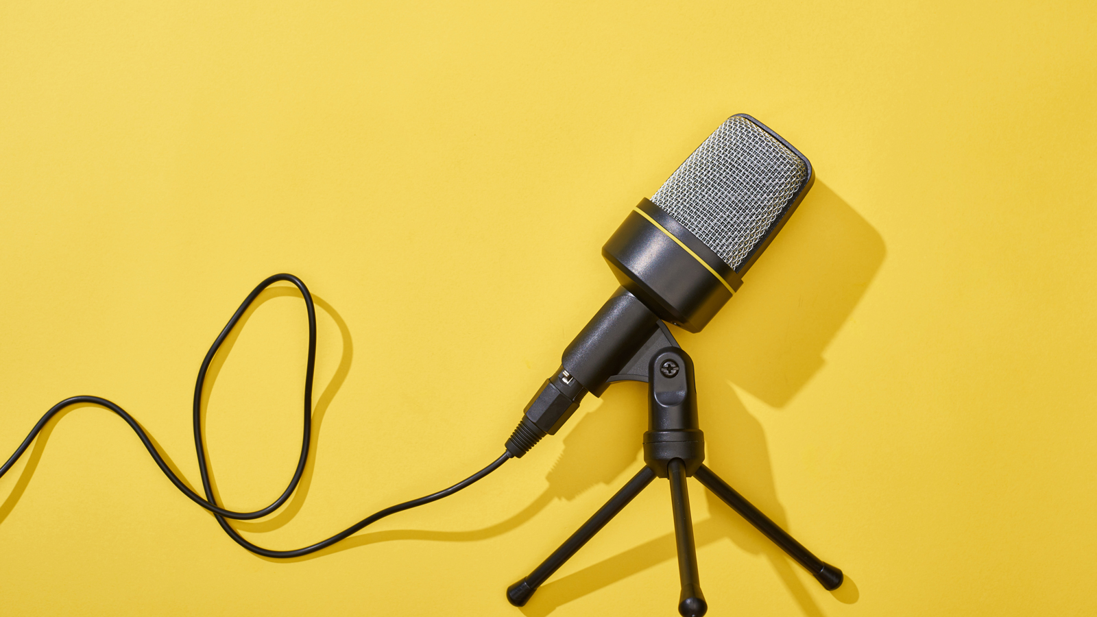 Image is of a Microphone of a stand with a vibrant yellow background