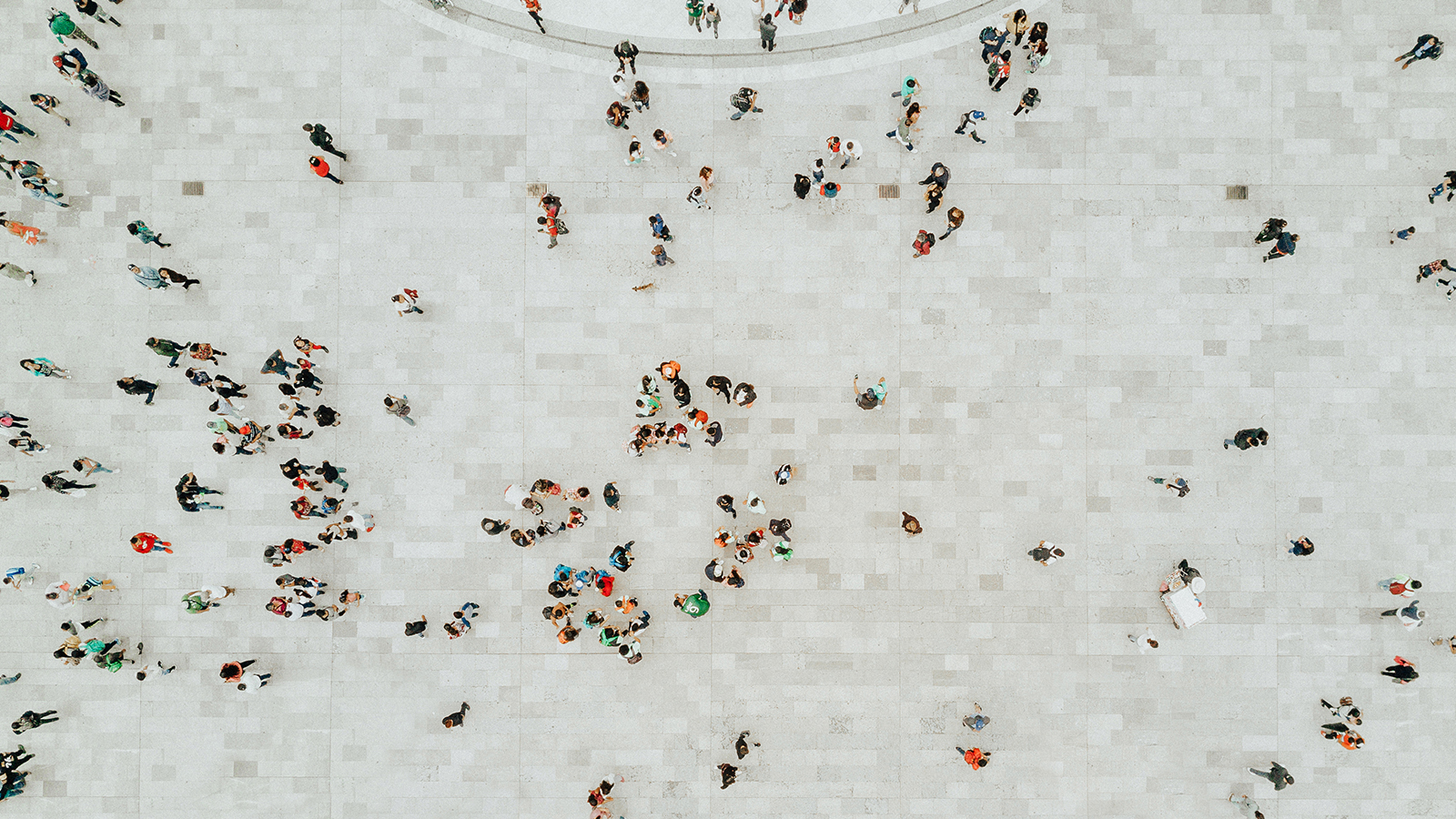 Image of aerial view of a a crowd of people scattered across an eggshell-coloured concrete space