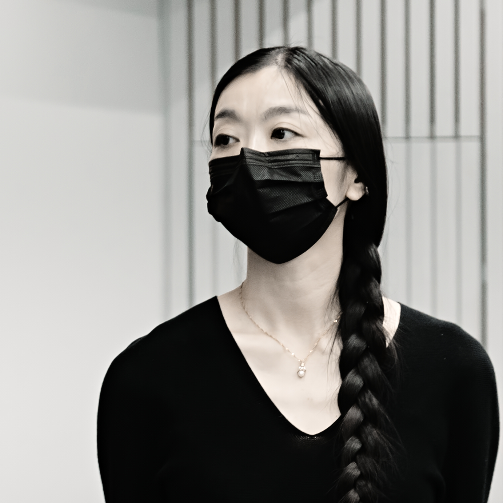 this image is of a woman in black with mask and long black hair in a plait