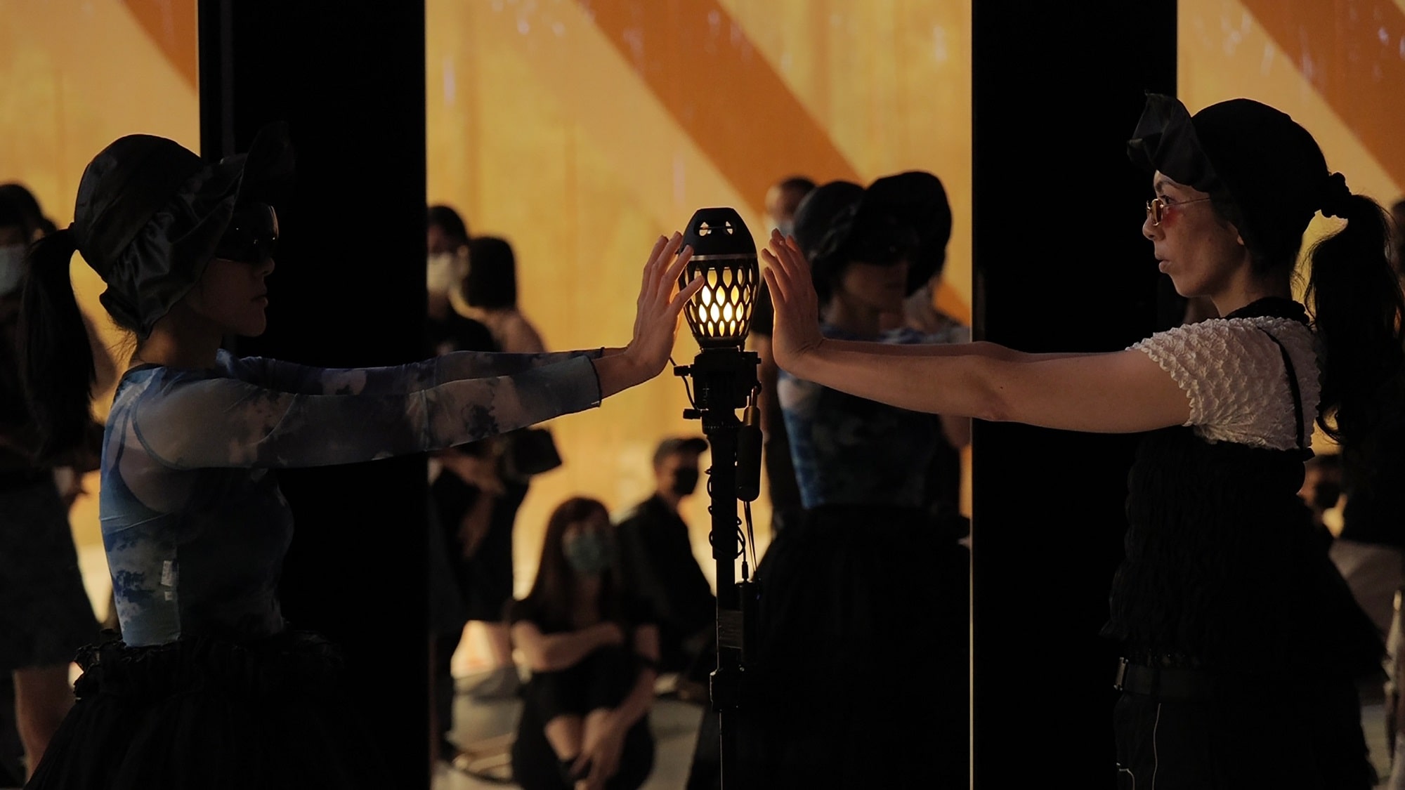 This image is of two women standing in front of the mirror and touching a torch shaped lamp.