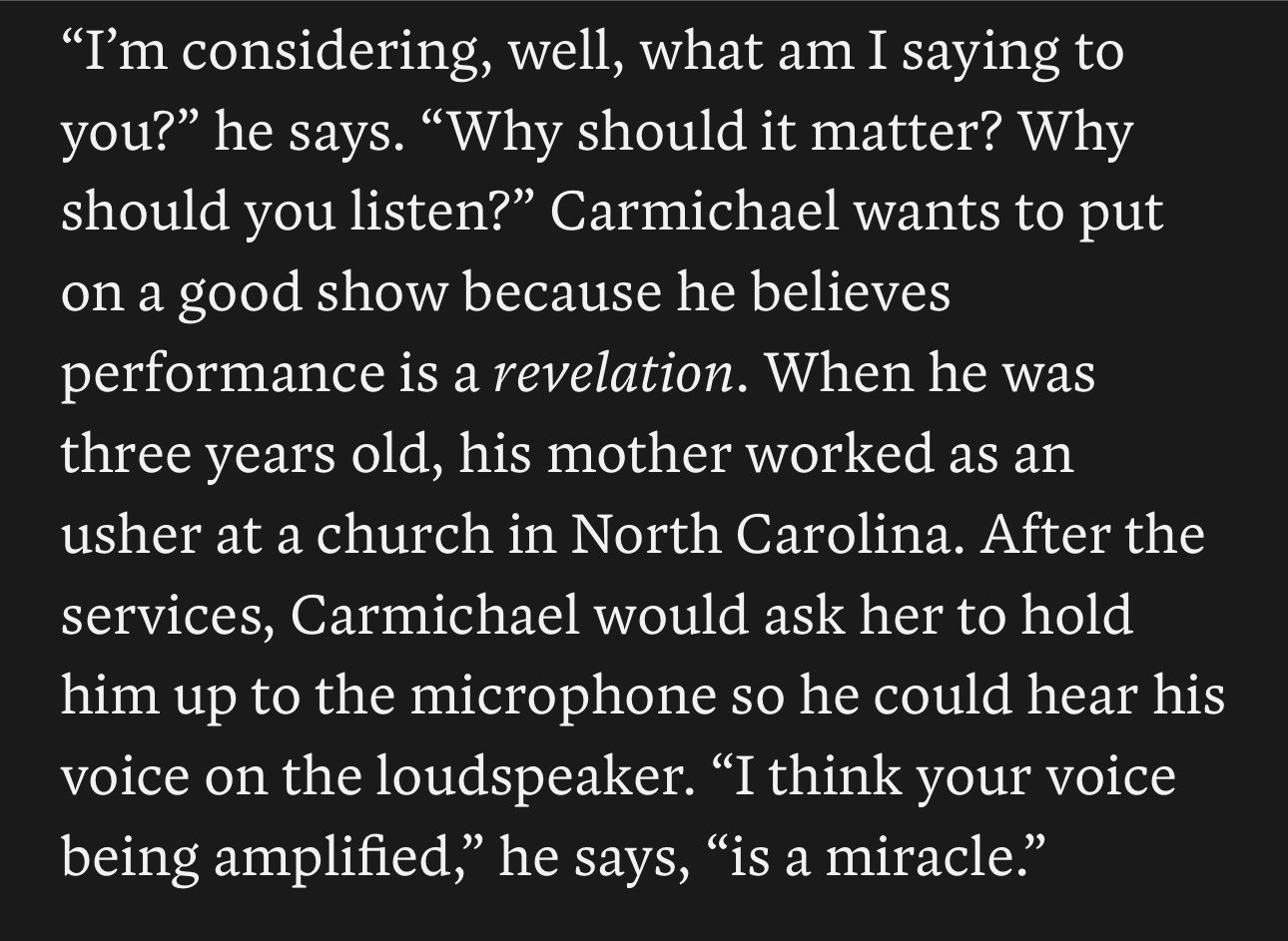 Screenshot of white text on a black background: "I'm considering, well, what am I saying to you?" he says. "Why should it matter? Why should you listen?” Carmichael wants to put on a good show because he believes performance is a revelation. When he was three years old, his mother worked as an usher at a church in North Carolina. After the services, Carmichael would ask her to hold him up to the microphone so he could hear his voice on the loudspeaker. “I think your voice being amplified,” he says, “is a miracle."